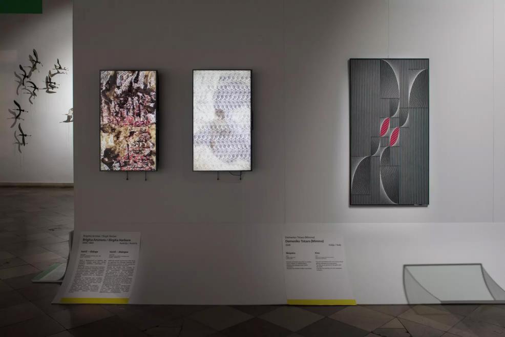 Three vertical works on the wall – two digital images and one geometric painting with red accents.