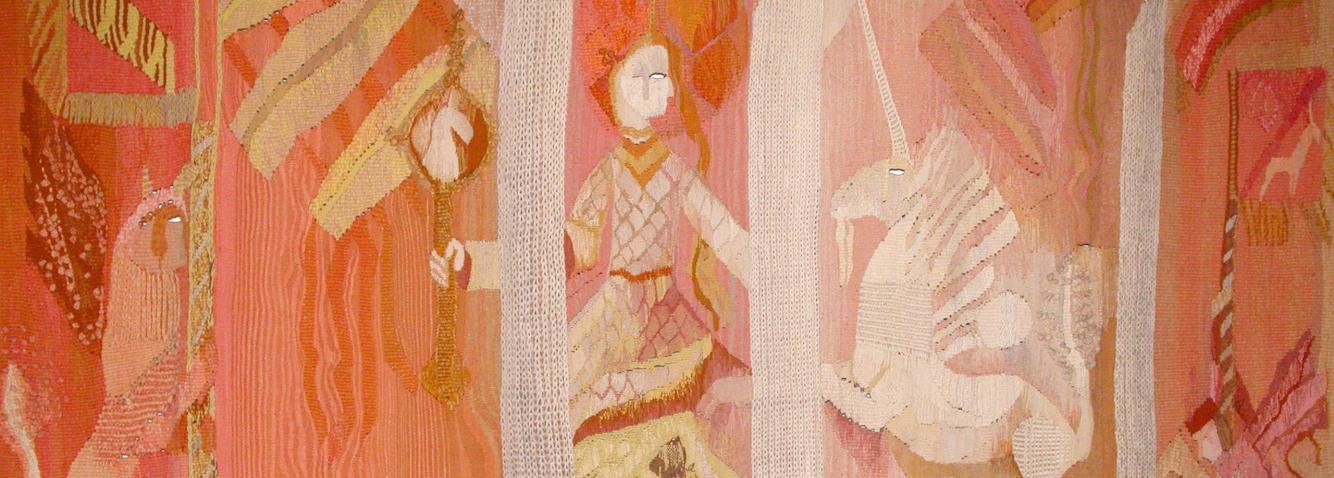 A textile artwork in warm pink and orange tones featuring stylised figures and mythological motifs arranged in decorative panels.