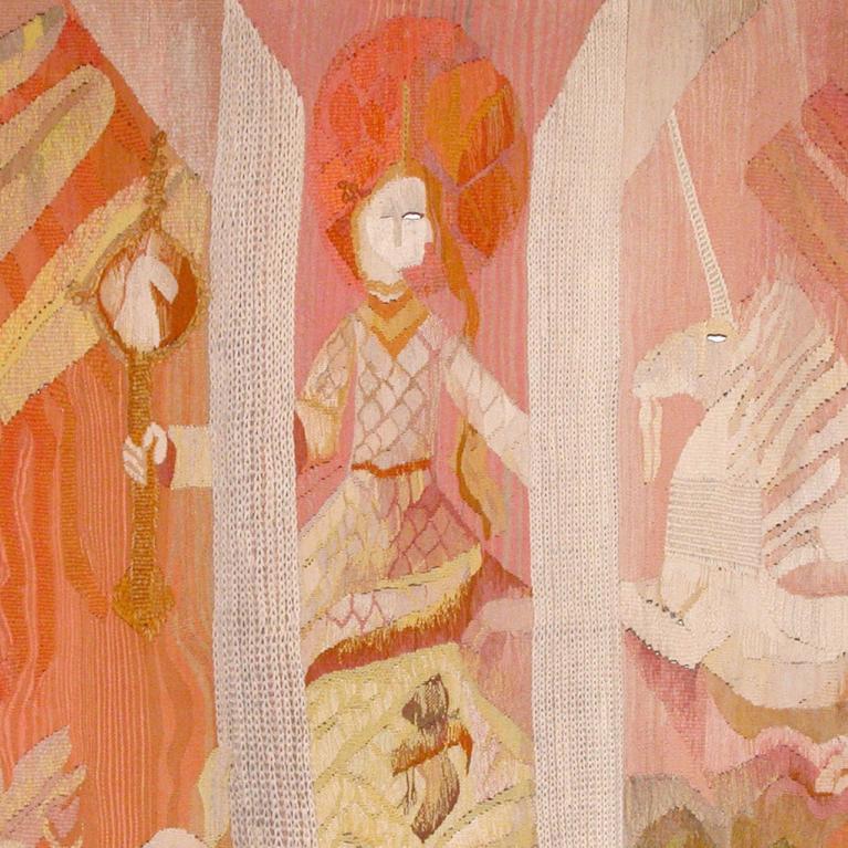 A textile artwork in warm pink and orange tones featuring stylised figures and mythological motifs arranged in decorative panels.