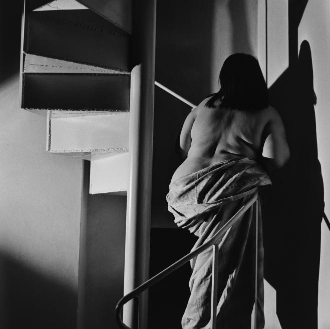 Black and white photo of a half-naked woman on the stairs.