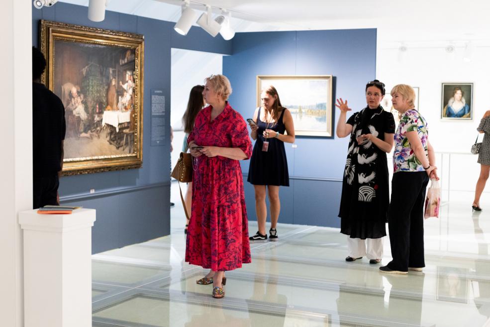 Visitors observing paintings at an art exhibition, with some people actively discussing the artworks.