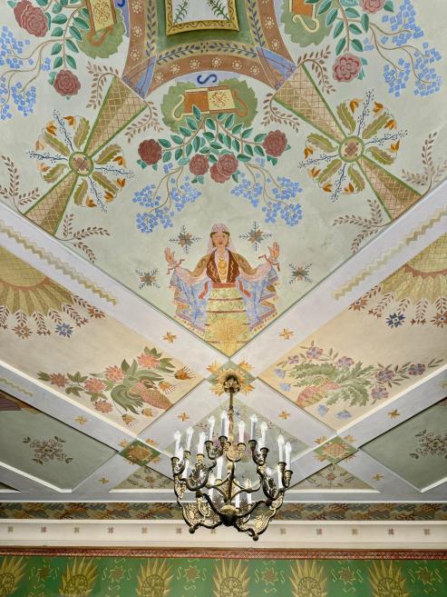 Anša Cīruļa gleznojums Rīgas pils Sūtņu zālē (1923–1929) ar tautas ornamentiem un sievietes figūru griestu dekorācijā.