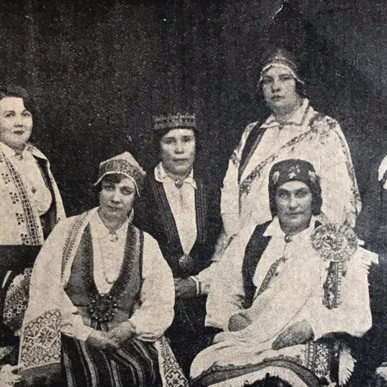 Vēsturiska fotogrāfija rāda Latvijas Sieviešu nacionālās līgas rūpniecības sekcijas dalībnieces tautastērpos un svinīgā pozā.