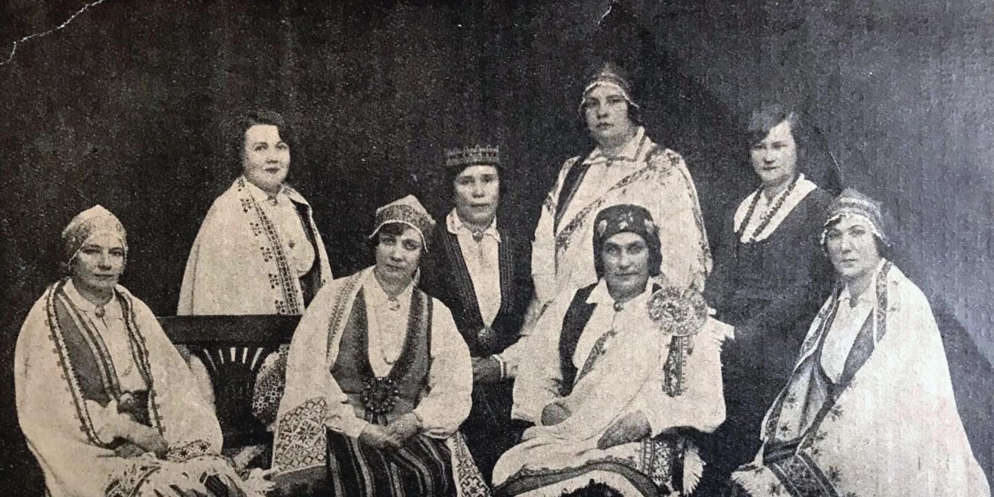 Vēsturiska fotogrāfija rāda Latvijas Sieviešu nacionālās līgas rūpniecības sekcijas dalībnieces tautastērpos un svinīgā pozā.