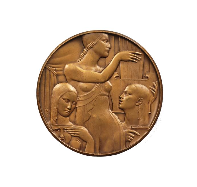 Bronzas apaļā medaljonā attēlota sievietes figūra profilā ar paceltu roku pie stīgām, ap kuru izvietotas vairākas seju reljefa galvas.