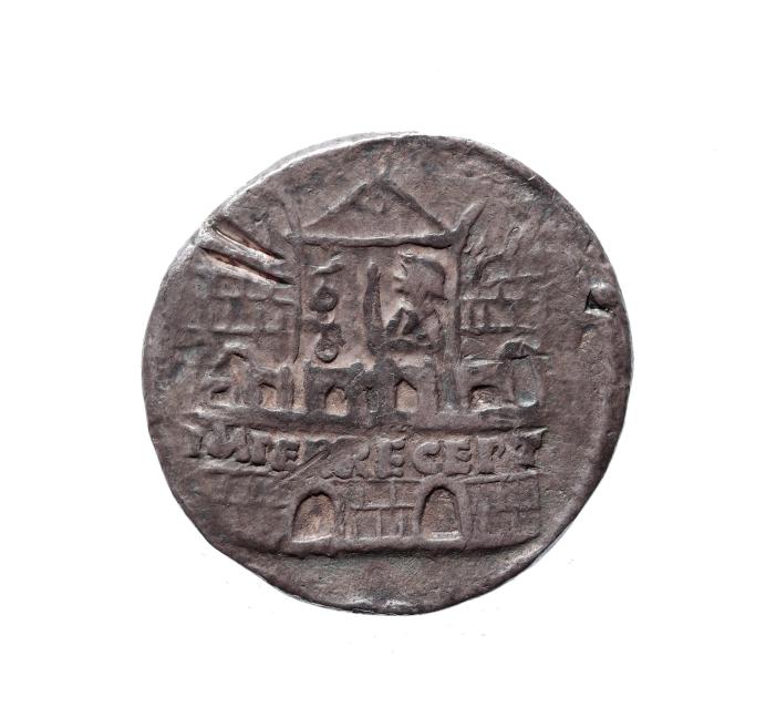 A round dark metal coin or medallion with a relief depiction of a building and an incised inscription on a white background.