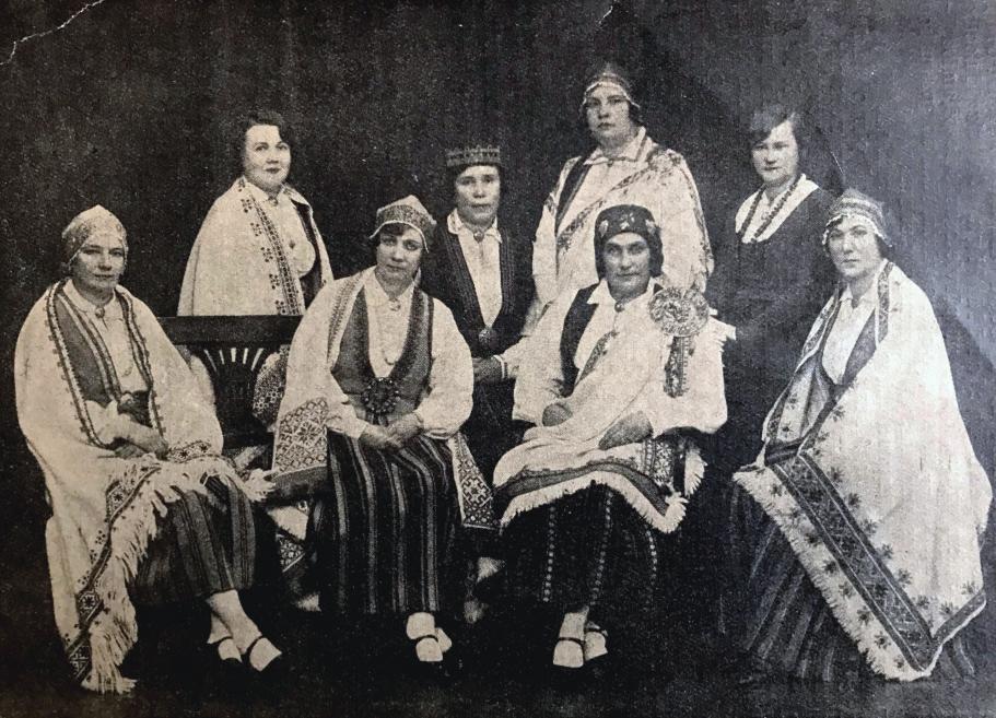 Vēsturiska fotogrāfija rāda Latvijas Sieviešu nacionālās līgas rūpniecības sekcijas dalībnieces tautastērpos un svinīgā pozā.