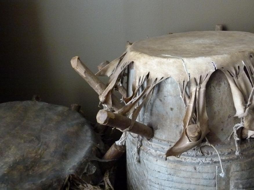 Ethnic drums made of wood and leather are visible in the foreground.