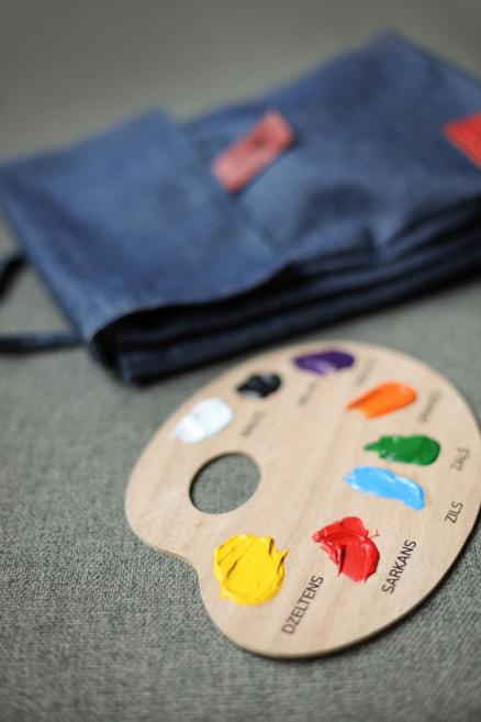 Koka krāsu palete ar dažādu toņu akrila krāsām uz galda.