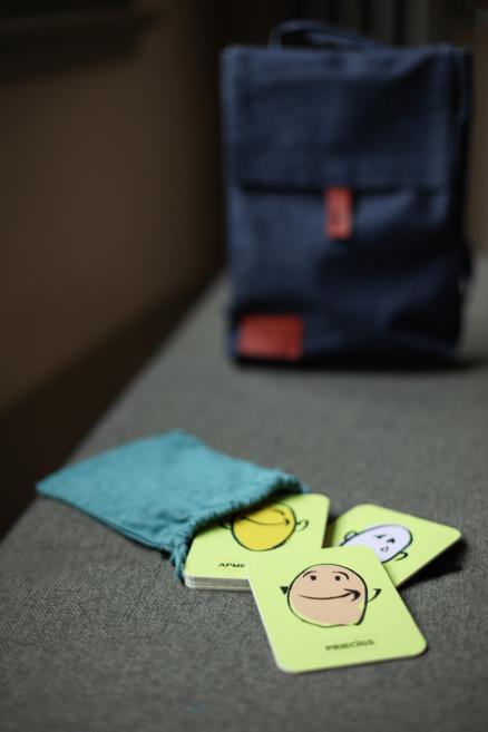 Emociju kartītes uz galda pie tumši zilas somas.