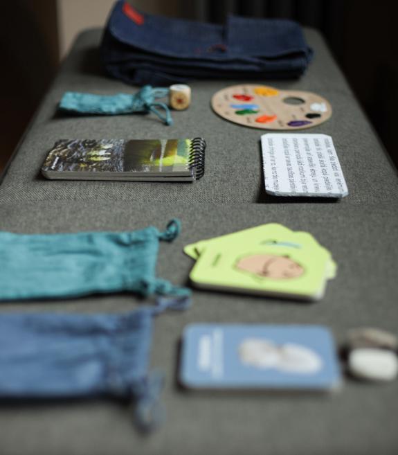 Dažādi mācību materiāli un krāsaina palete sakārtoti uz galda.