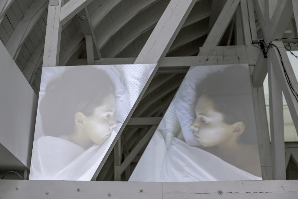 Video projection with sleeping artists at the exhibition.