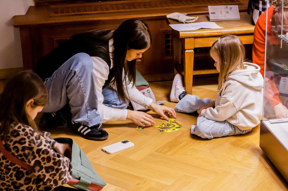 Meitene liek kopā dzeltenu puzli ar pūķa attēlu.