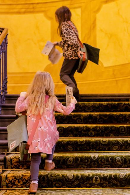 Divas meitenes ar ceļojuma somām kāpj pa muzeja kāpnēm.