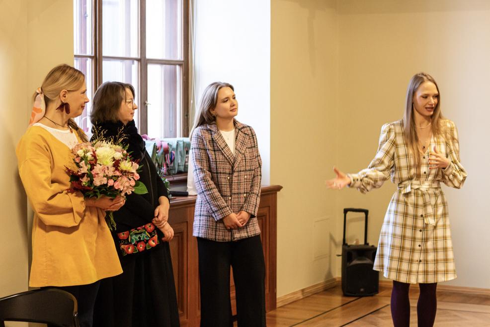 Sieviete uzrunā klātesošos muzeja pasākumā.