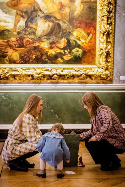 Sieviete un bērns pēta priekšmetus somā muzeja zālē.