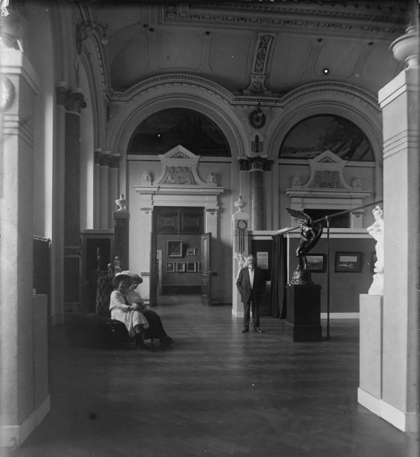 Muzeja iekštelpu fotogrāfija ar apmeklētājiem un mākslas darbiem Rīgas pilsētas mākslas muzejā, 1911. gads.