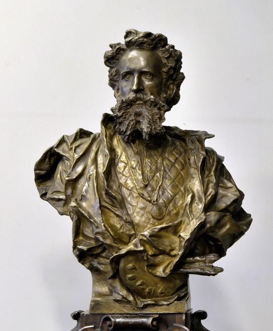 Bronze bust of a bearded man in a draped cloak against a light background.