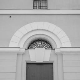 Black and white architectural detail with a semicircular window and decorative arch on the facade.