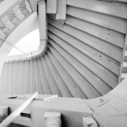 Black and white view of wooden stairs from above with a spiral curve.