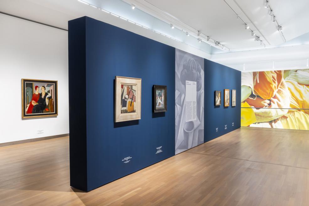 Uz tumši zilas izstāžu sienas eksponētas vairākas klusās dabas un modernisma gleznas.