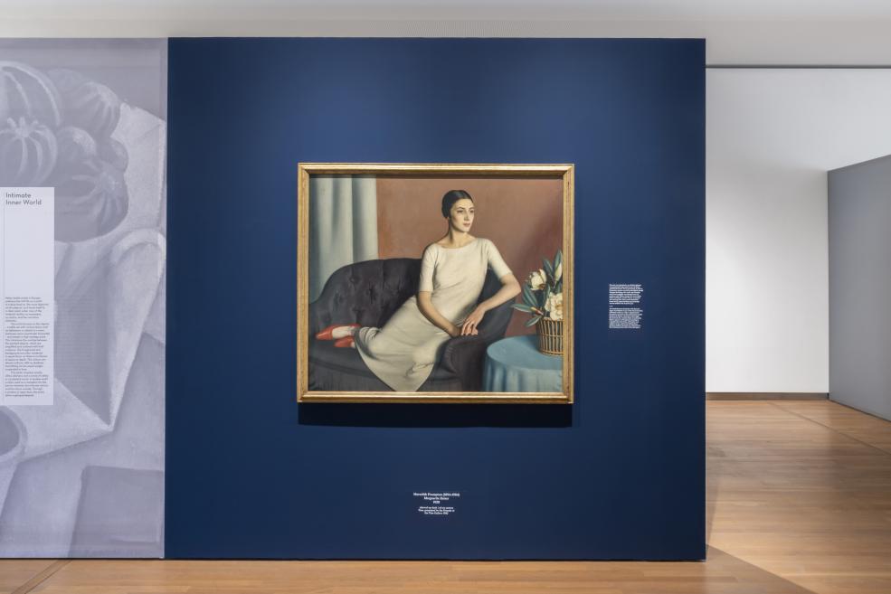 Uz tumši zilas izstāžu sienas eksponētas vairākas klusās dabas un modernisma gleznas.