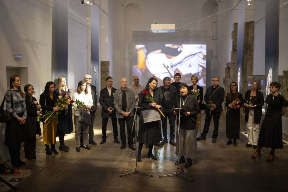 Two women perform at a jewelry exhibition with the audience in the background