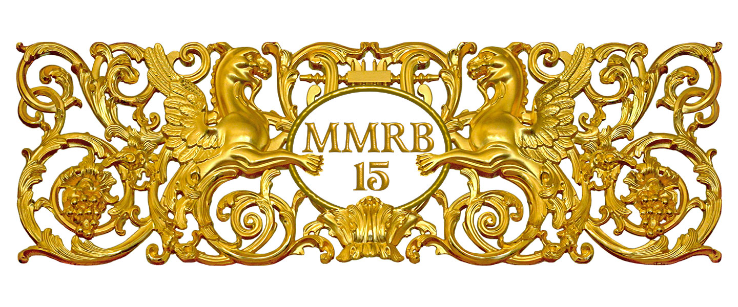 Zeltīts dekoratīvs ornaments ar diviem spārnotiem grifiem, vīnogu ķekariem un centrālu medaljonu ar uzrakstu “MMRB 15”.