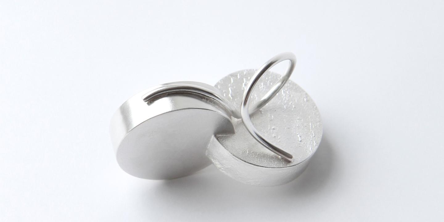 Two interconnected silver-toned metal rings on a white background.