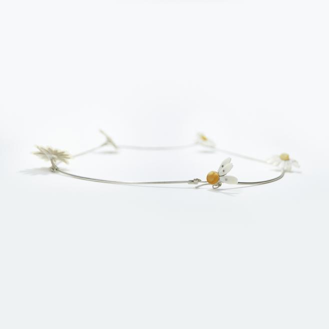 Thin metal necklace with small daisy motifs and yellow centers on a light background.
