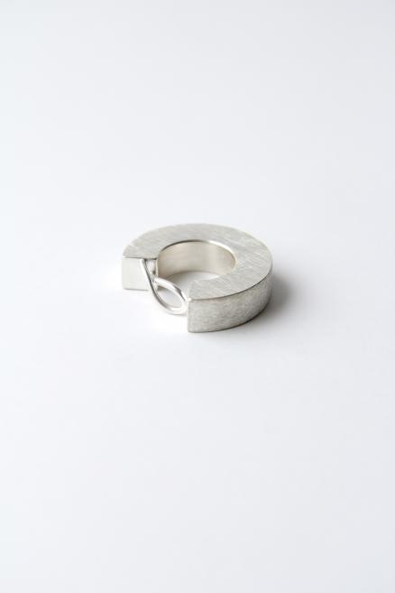 Matte metal ring with an open circular shape placed on a light background.