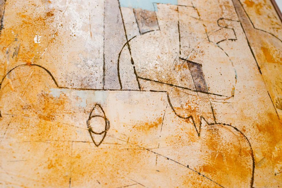 An abstract painting in warm ochre-yellow tones, featuring fine incised lines and geometric shapes on a textured surface.