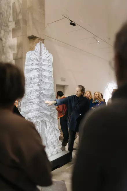 Mākslinieks iepazīstina ar stikla objektu izstādē.