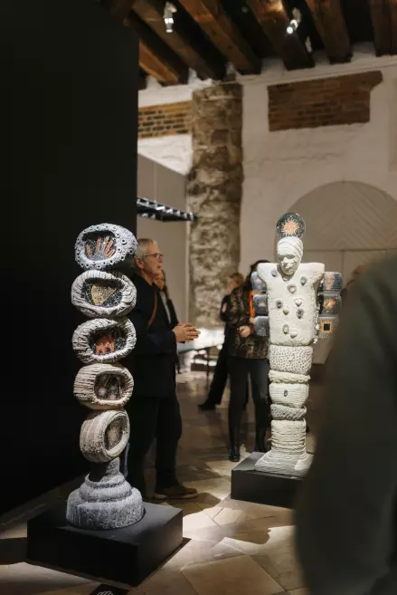 Mākslinieks iepazīstina ar stikla objektu izstādē.