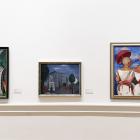 Muzeja sienā izkārtotas vairākas gleznas, tostarp ainava un divu figūru kompozīcija spilgtās krāsās.