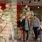 Muzeja zālē ar klasiskām skulptūrām apmeklētāji aplūko eksponātus un lasa informācijas materiālus.