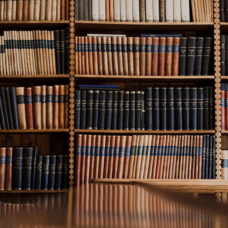 Plaukti piepildīti ar grāmatām bibliotēkas telpā ar koka interjeru.