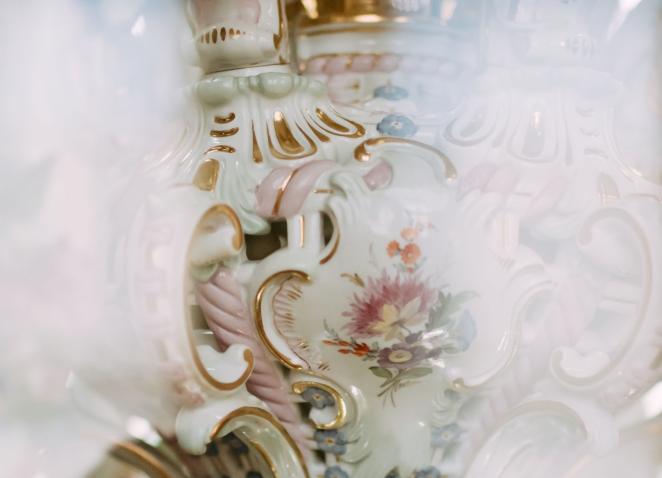 Detail of a decorative porcelain vessel with floral ornament and gilded decorative lines.