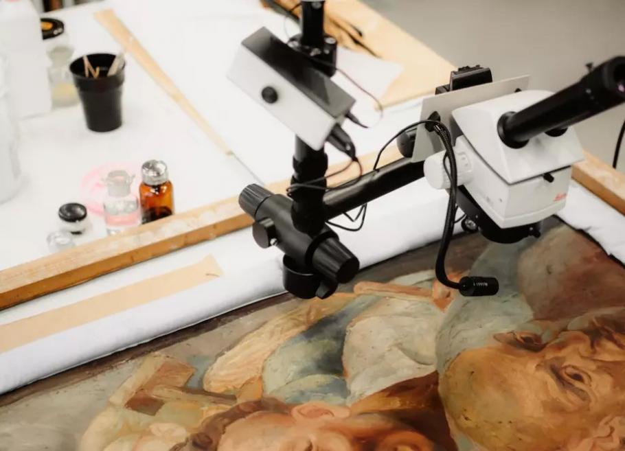 Restoration of a painting using a microscope in a conservation studio.