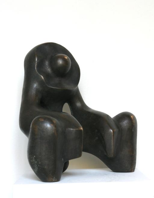 Dark abstract bronze sculpture with rounded forms on a white pedestal.