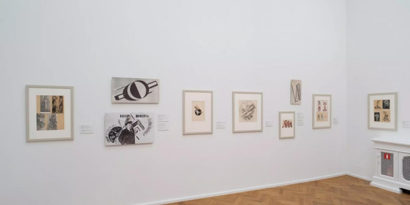 Exhibition wall at the Latvian National Museum of Art displaying early 20th-century graphic works and typographic compositions.