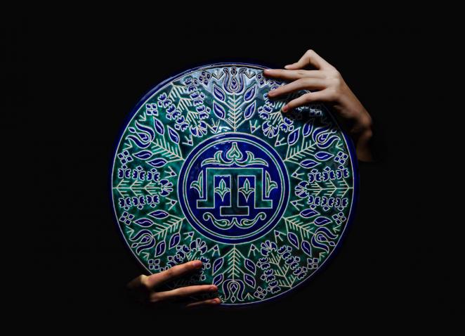 rokās ornamentāls šķīvis.