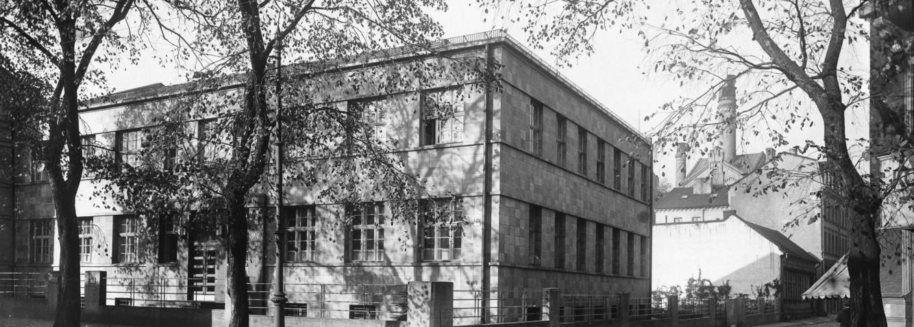 Historical black-and-white photograph of a modernist-style building in Riga, surrounded by trees with falling leaves.