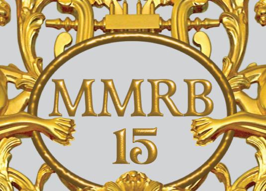 Zeltīts dekoratīvs ornaments ar diviem spārnotiem grifiem, vīnogu ķekariem un centrālu medaljonu ar uzrakstu “MMRB 15”.