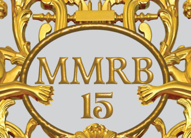 Zeltīts dekoratīvs ornaments ar diviem spārnotiem grifiem, vīnogu ķekariem un centrālu medaljonu ar uzrakstu “MMRB 15”.