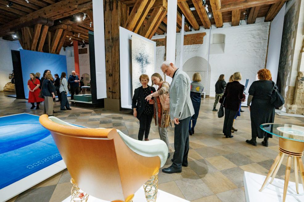 Muzeja izstāžu zālē apmeklētāji aplūko eksponātus, tostarp dizaina mēbeles un mākslas darbus plašā telpā.