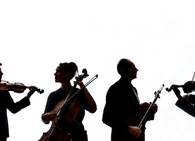 Četri mūziķi silueta attēlā spēlē stīgu instrumentus – divas vijoles, altu un čellu.