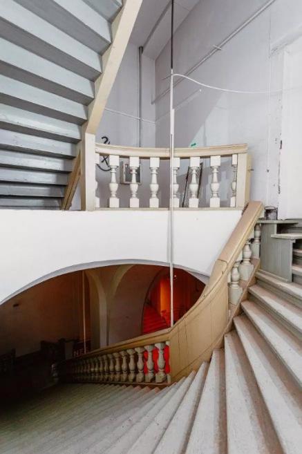 A spiral staircase landing with balustrades and multiple flights in the historic interior.