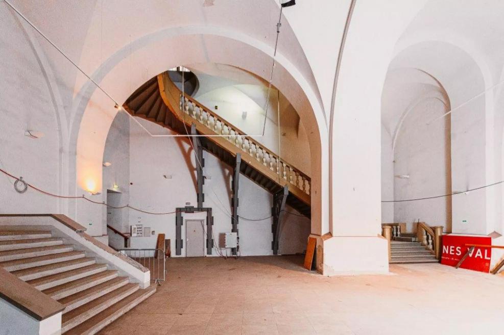 A large hall with high arched ceilings and massive stairs in Riga Arsenāls.