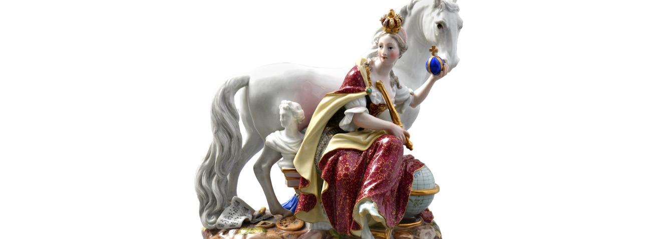 Porcelain figurine of a seated crowned woman with a white horse on a decorative base.